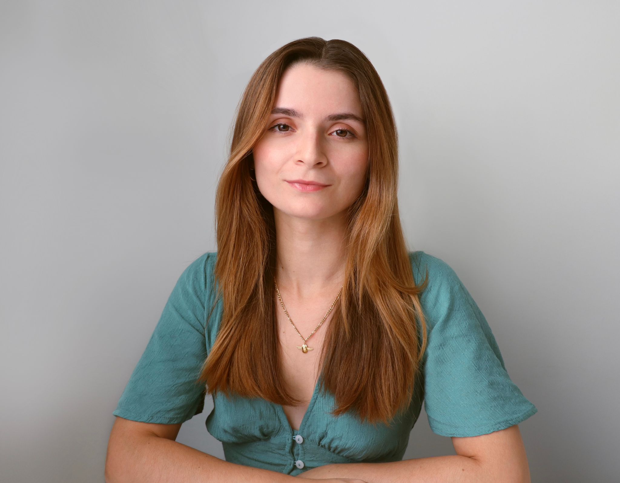 Marta Rivera, autora de 'La Aventura de Lou', sonríe mientras sostiene su libro, rodeada de ilustraciones coloridas y un entorno natural inspirador.